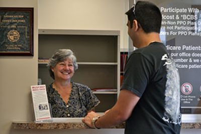 A patient checking in at the front desk for their appointment