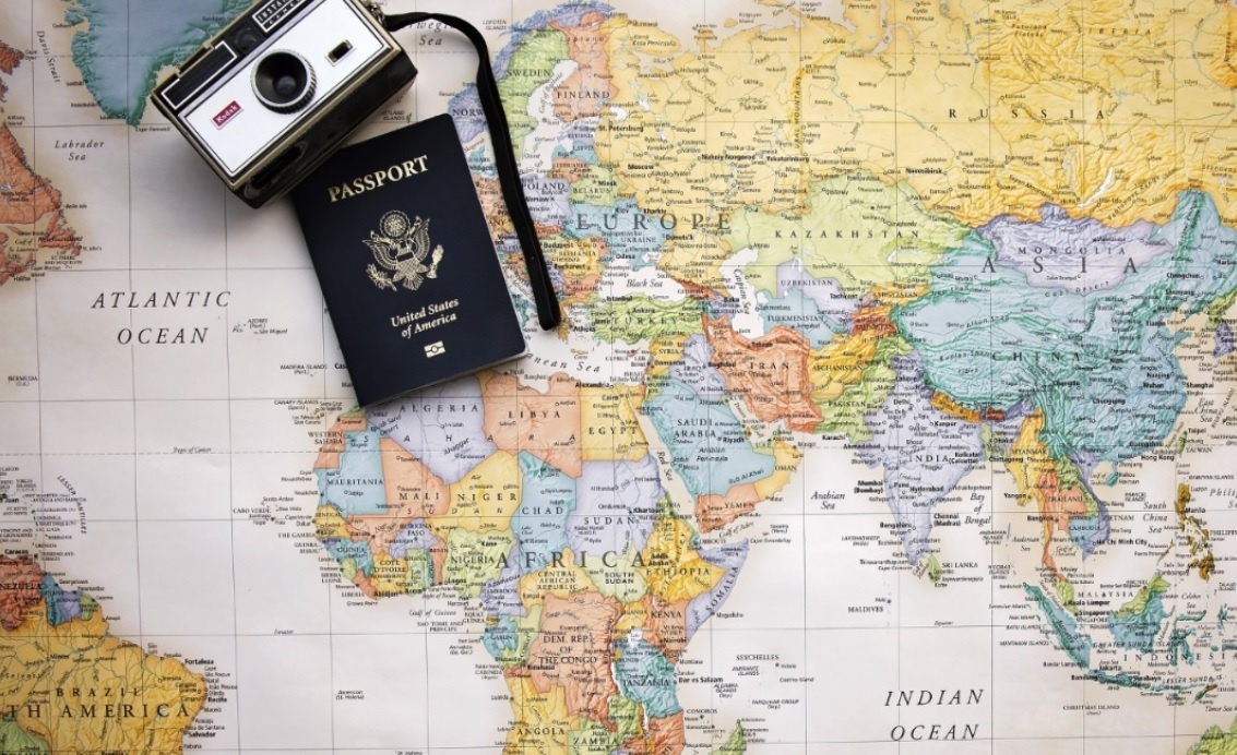 A camera and passport resting on a map of Europe and Africa